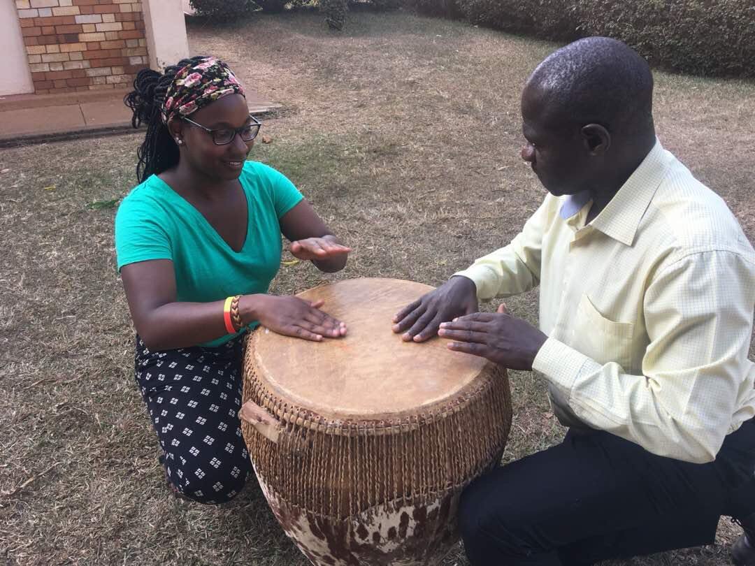 Mercer University alumna and Peace Corps volunteer beats a drum with a man in Uganda